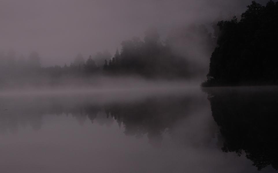 Durch seine längliche Grundform und die bewaldeten Ufer ist das Wasser des Lake Matheson häufig spiegelglatt, so dass sich gerade in den Morgen- und Abendstunden die Reflexionen der südöstlich liegenden Berge zeigen.