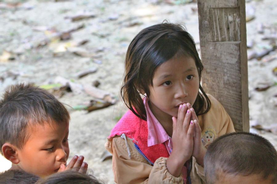 Kinder beim Beten an einer Buddha-Statue.