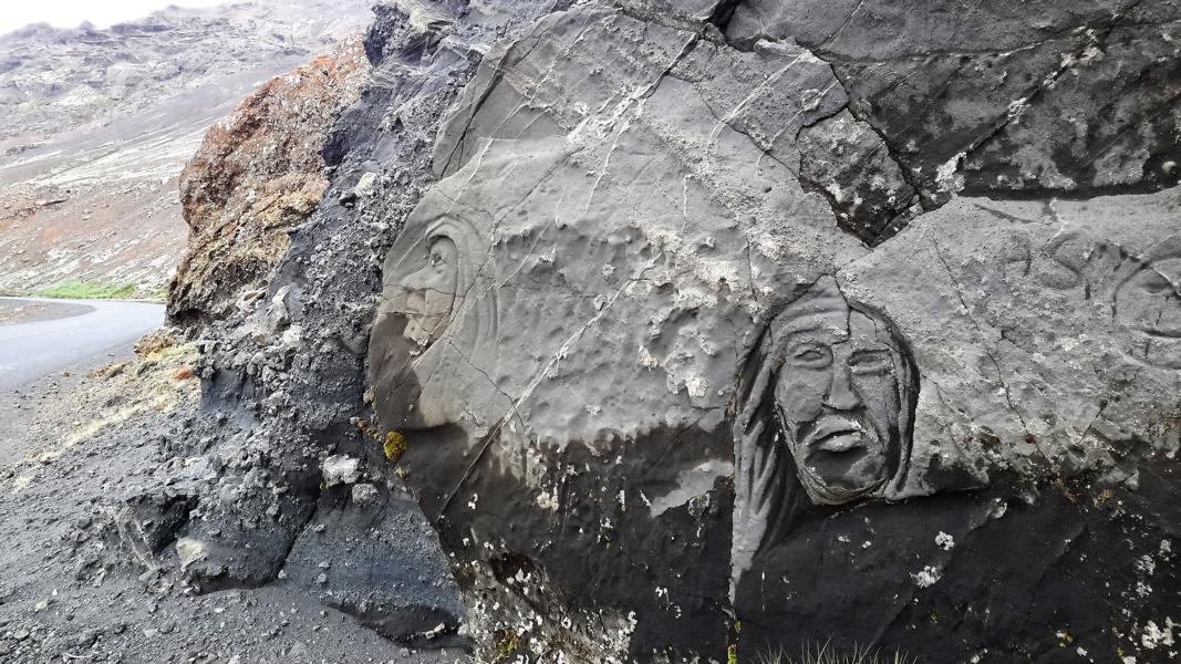 In Sandstein gemeiselte Gesichter am Kleifvatn